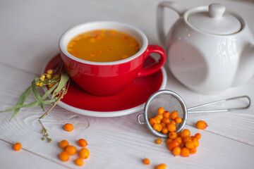 Obraz na płótnie Canvas Herbal hot tea with buckthorn and honey on white wooden background. Hot drinks with vitamins
