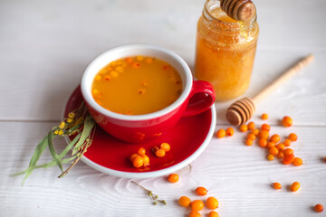 Herbal hot tea with buckthorn and honey on white wooden background. Hot drinks with vitamins