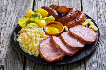 bratwurst, pork, potatoes, sauerkraut on a plate