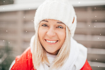 woman with frost eyelashes on frosty winter day in knitted white hat looking at camera and laughing