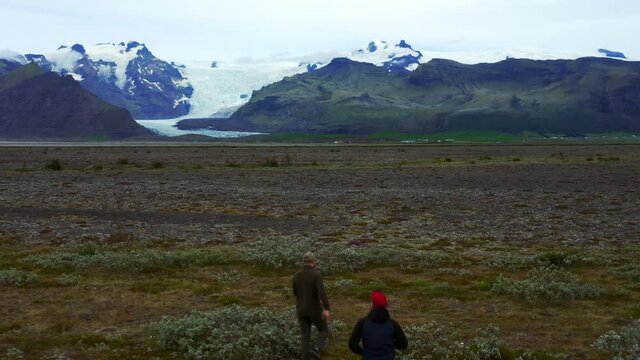 Men Running On The Field At Skeidararsandur With Svinafellsjokull Glacier In The Distance. - aerial