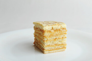 Slice of honey layer cake on white plate. Side view. Layer cake, close-up