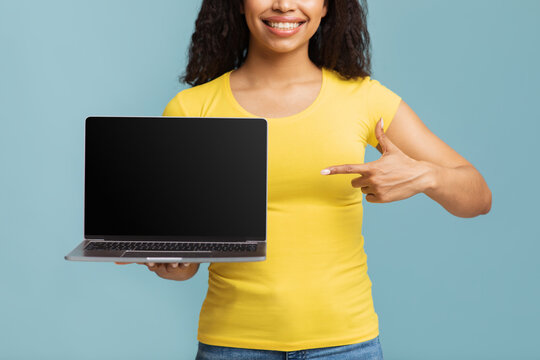 Featured website and online advertising. Young african american lady pointing finger at laptop with blank screen, crop
