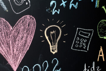 school board with formulas and drawings drawn in chalk. light bulb, heart, calculator