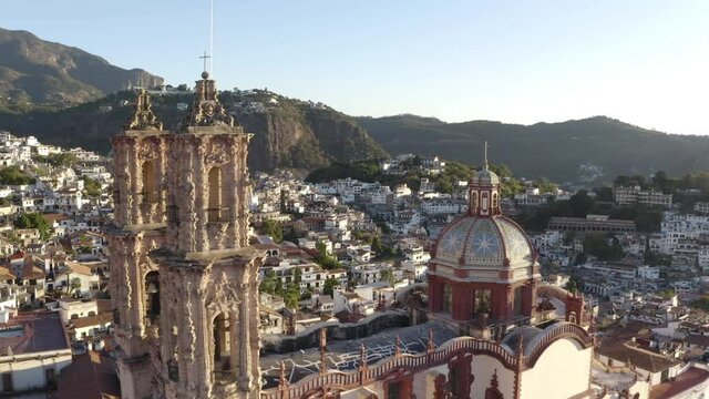 Aerial View of Santa Prisca Church, Historic Colonial Landmark of Taxco City, Mexico. Temple and Downtown Neighborhood on Golden Hour Sunlight - Drone Shot
