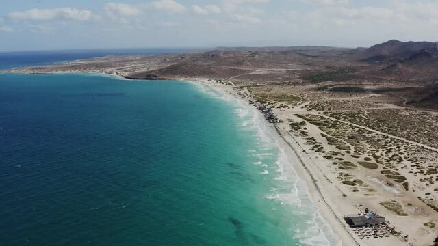 Drone pans over the blue coastline of Tecolote Beach.
