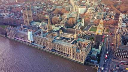 Fototapeta premium Aerial drone photo of iconic City of Westminster with houses of Parliament, Big Ben and Westminster Abbey in front of river Thames at sunset, London, United Kingdom