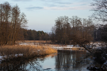 River bank, dry grass, snow and frozen water