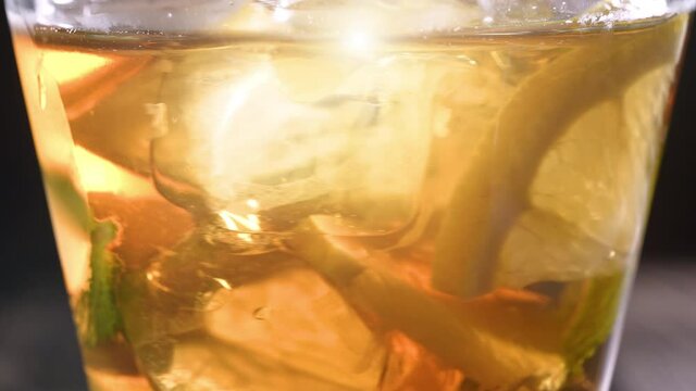 Iced tea in the glass with ice cubes and sliced lemons. Healthy refreshing lemonade for detoxification, sweet tasty soft drink or cold aromatic beverage for summer time in slow motion