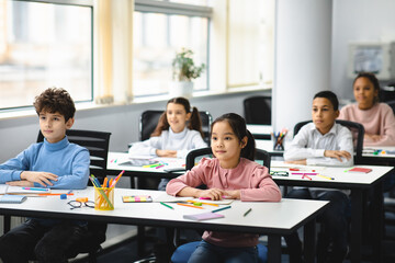 Fototapeta Portrait of focused diverse pupils sitting at desk in classroom obraz
