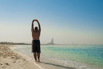 Fototapeta na wymiar Training a guy on the beach. Healthy, fitness, wellness lifestyle. Sport, cardio, workout concept