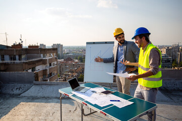 Fototapeta premium Team of architects people in group on construciton site check documents and business workflow.