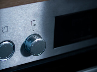 Kitchen oven, close-up rotary switch to choose a program for the baking oven.  Front of the stove in brushed metallic. 