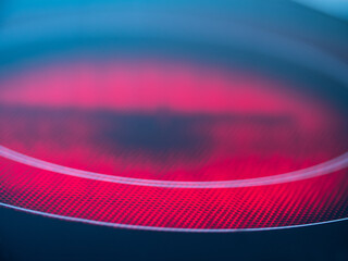 Close-up of kitchen stove with ceramic hob turned on and glowing red. 