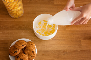 Children breakfast, corn and oatmeal fruit rings with milk in a bowl on a light gray background