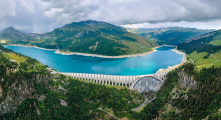 Obraz na płótnie Canvas Hydroelectric dam and reservoir lake in French Alps mountains. Renewable energy and sustainable development with hydropower generation. Aerial view.