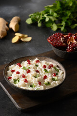 Curd Rice with pomegranate, cilantro, mustard seeds, ginger on a black background. Indian South cuisine. Vertical orientation.