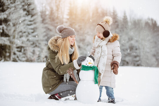 Parent and child playing in snow. Build a Snowman.