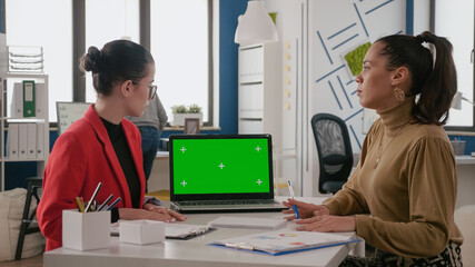 Team of women working with green screen on laptop in business office. Coworkers using mock up...