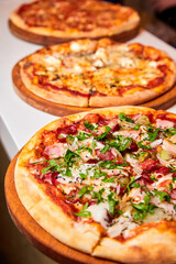 Pizza with salami, bell pepper, tomatoes and cheese, pickles, bacon and sausages on a light background. Close-up, selective focus