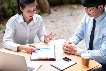 Obraz premium Young business woman and businessman talking and looking financial report on document