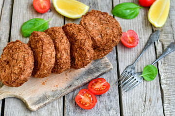 Home made  pork meatballs with  fresh cherry tomatoes on wooden rustic background. Deep fried minced  meat patties on cutting board.