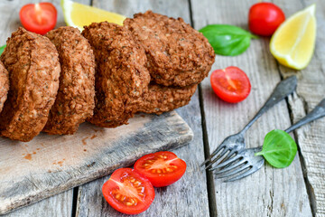 Home made  pork meatballs with  fresh cherry tomatoes on wooden rustic background. Deep fried minced  meat patties on cutting board.