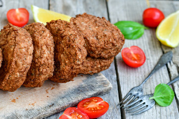 Home made  pork meatballs with  fresh cherry tomatoes on wooden rustic background. Deep fried minced  meat patties on cutting board.