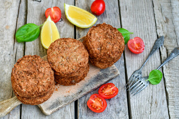 Home made  pork meatballs with  fresh cherry tomatoes on wooden rustic background. Deep fried minced  meat patties on cutting board.