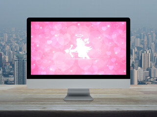 Cupid flat icon on desktop modern computer monitor with red love heart screen on wooden table over city tower and skyscraper, Business internet dating online, Valentines day concept