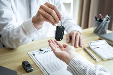Obraz na płótnie Canvas Salesman agent sending a key to customer after the good deal agreement, successful car loan insurance contract buying or selling new vehicle