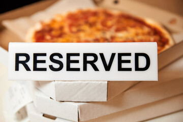 Plastic plaque with the inscription Reserved on the open box with pizza.