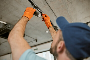 Male hands in gloves repairing ceiling lamp