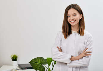 Smiling female doctor with arms crossed standing at her doctor office and looking at camera....