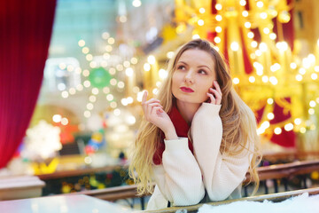 happy blond girl in red scarf close up portrait on decorated Christmas city mall background