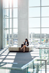 She masters the art of communication. Full length shot of an attractive young businesswoman using a smartphone while sitting in a waiting room.