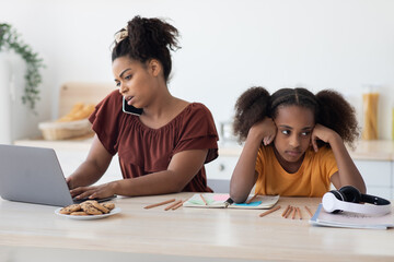 Angry teen girl sitting by working mom, kitchen interior