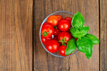 Red ripe cherry tomatoes, green basil in glass. Studio Photo