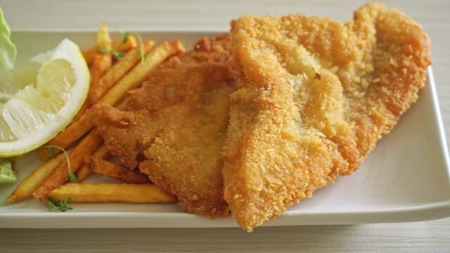 fish and chips - fried fish fillet with potatoes chips and lemon on white plate