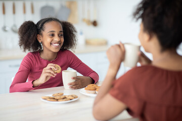 Cute african american girl drinking tea with her mom