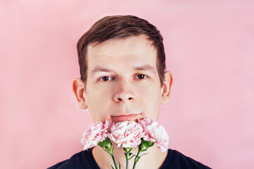 Portrait of a man with flowers near his face on a pink background. Birthday, mother's or valentine's day gift