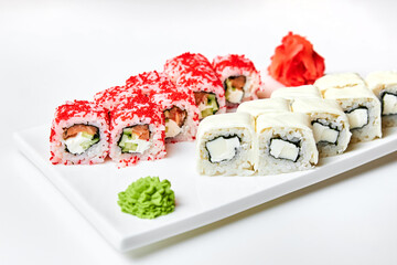 Rolls with salmon and cucumber, cheese and wasabi on a white plate.