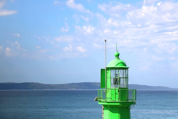 Fototapeta na wymiar Green lighthouse in the port of Split, Croatia and bright blue sky.