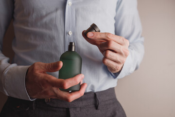 Man in formal wear holding perfume bottle, closeup. 