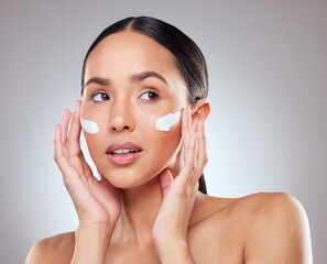 For sensitive skin, choose a moisturiser with soothing ingredients. Studio shot of a beautiful young woman applying moisturiser to her face against a grey background.