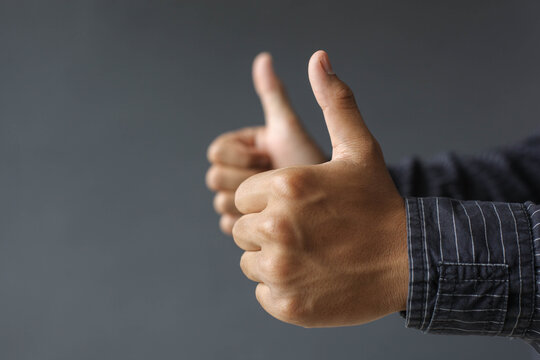Side view of the employee's hand giving two thumbs up isolated on gray background