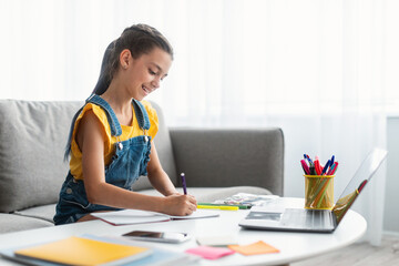 Girl sitting at desk, drawing in copybook