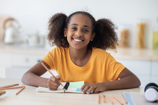 Cheerful african american teen girl doing homework