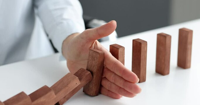 Risk and strategy in business is hand stopping the fall of wooden block