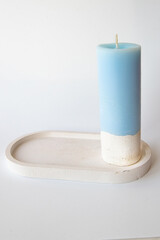 One Elegant Blue Hand made Candle on Concrete Stand on white background Home Decor Details. Flare Copy space Close-up Vertical image